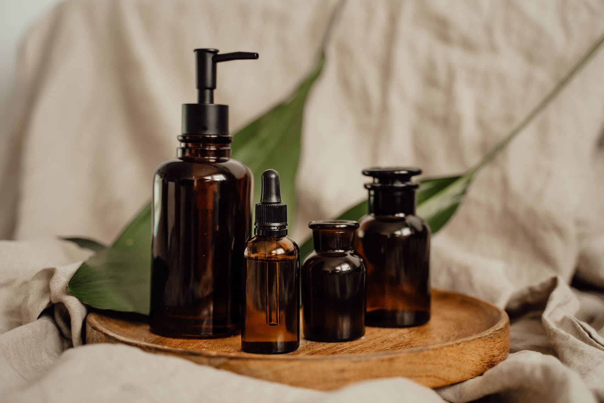 Amber glass dropper bottles arranged on a wooden tray in soft natural light