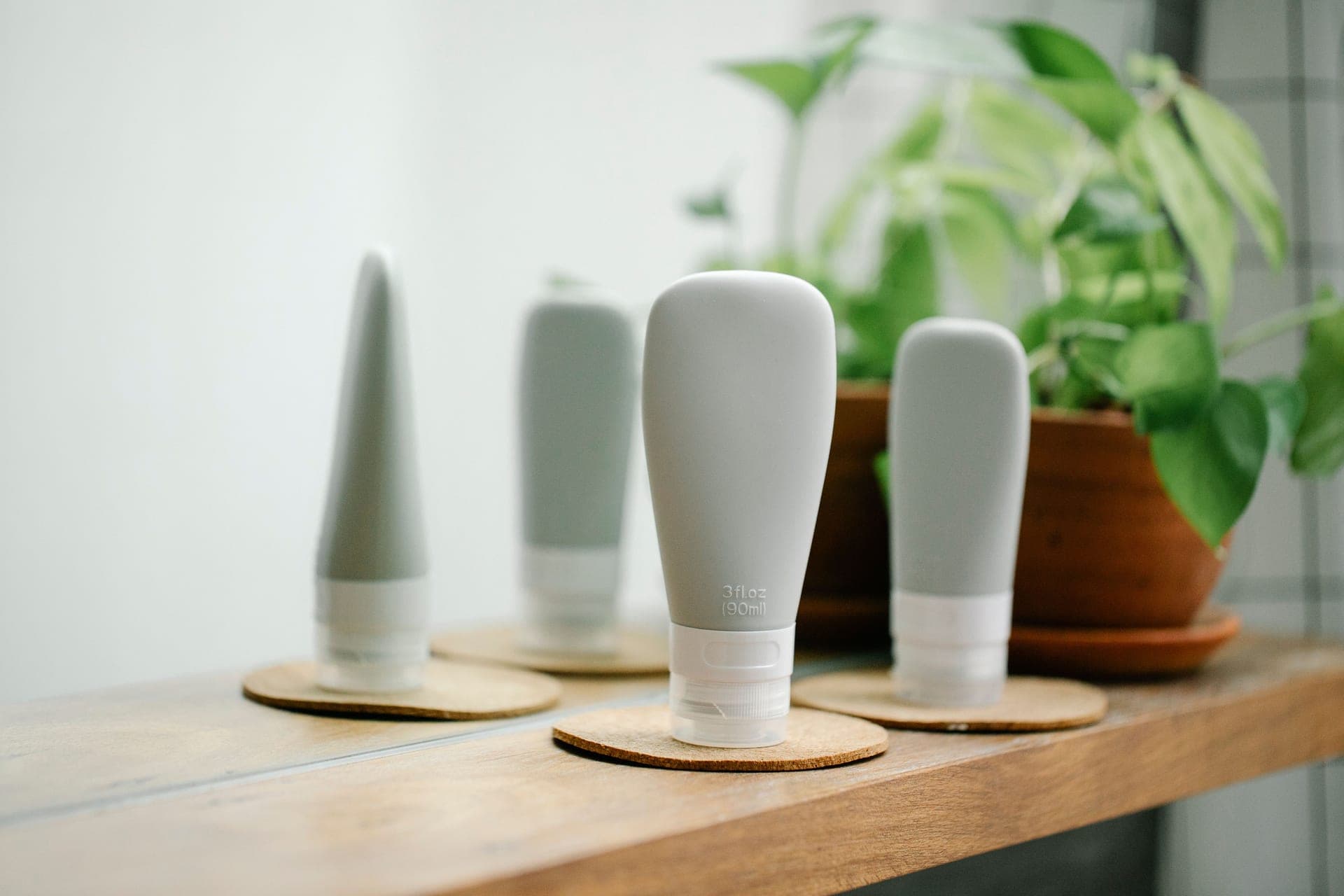 A small shelf of unbranded skincare bottles in morning light